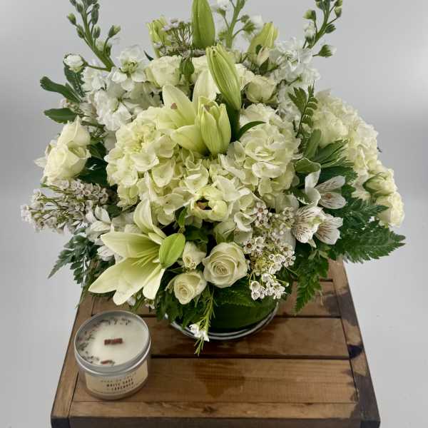 White floral arrangement with lilies, roses, and hydrangeas in a green vase