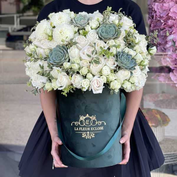 Large white rose and succulent arrangement in a dark green hatbox