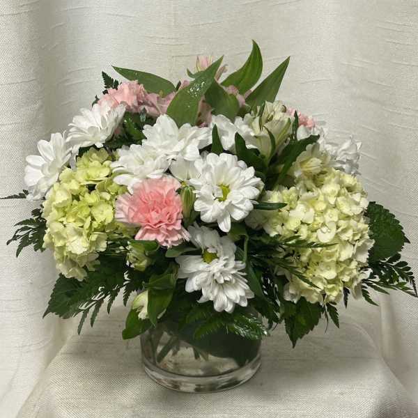 Pink and white flowers arranged in a clear glass vase