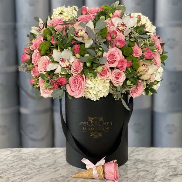 Pink roses and white orchids in a black hatbox with a small rose cone