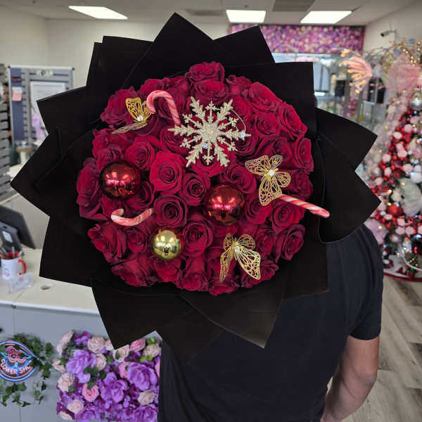 Bouquet of red roses with candy cane and ornament decorations in black wrap
