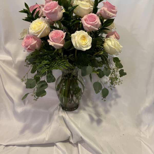 Pink and white roses arranged in a glass vase