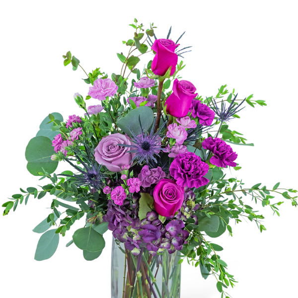 Tall arrangement of purple and hot pink roses and carnations in a clear glass vase