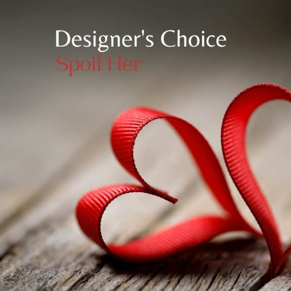 Red ribbon curled into a heart shape on weathered wood with text reading Designer's Choice Spoil Her