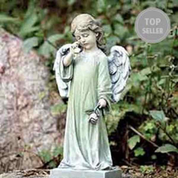 Garden angel statue in a pale green robe holding a small flower