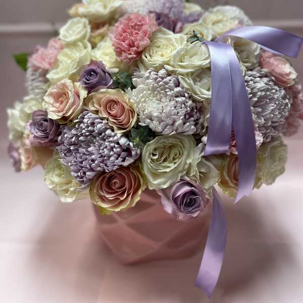 Bouquet of pastel roses and chrysanthemums in a pink box with a lavender ribbon