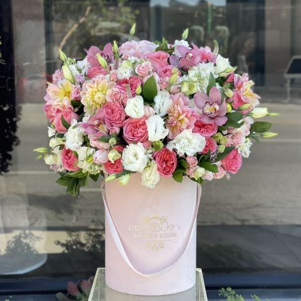 Large pink and white mixed flower arrangement in a round box