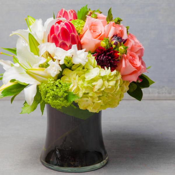 Pink roses and white lilies arranged in a dark glass vase
