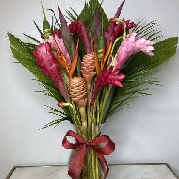 Tropical bouquet with pink and red ginger flowers in a glass vase