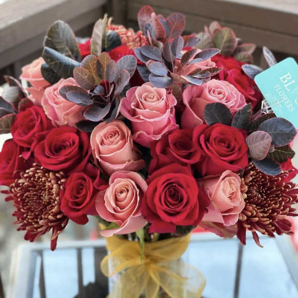 Bouquet of red and pink roses with dark foliage and burgundy blooms