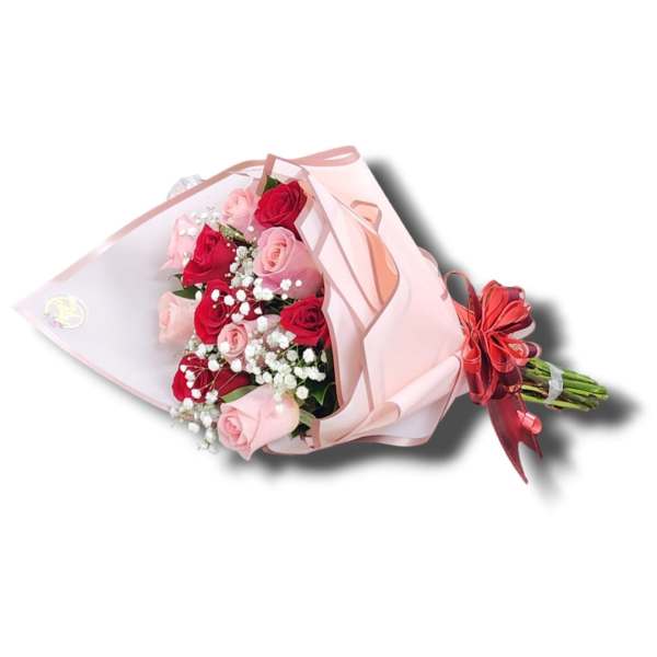 Bouquet of red and pink roses with white filler flowers wrapped in pink paper with red ribbon