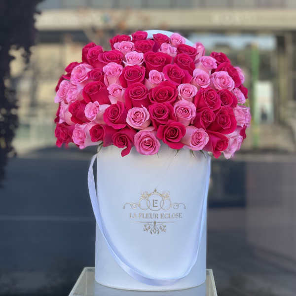 Pink and hot pink roses arranged in a white hat box