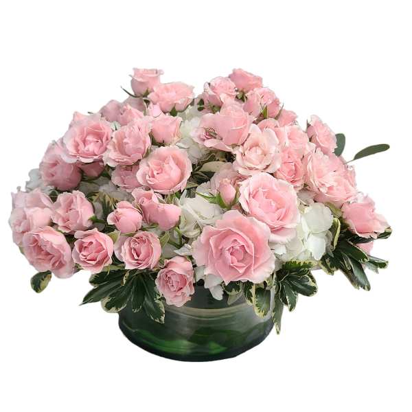 Pink roses arranged in a low green glass bowl with white flowers