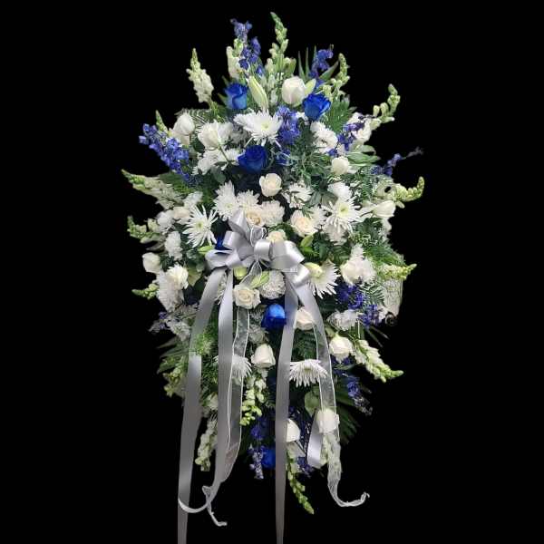 Standing floral spray with white and blue flowers and a silver ribbon