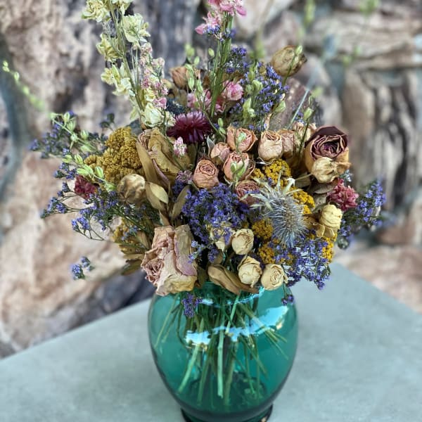 Dried flower bouquet in a teal glass vase