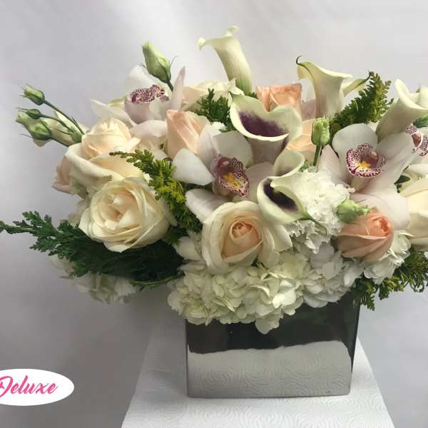 Cream roses and calla lilies in a square vase