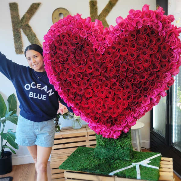Large heart-shaped rose display with a person standing beside it