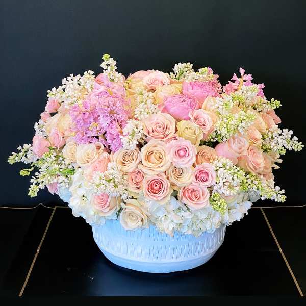 Large pastel rose arrangement in a white bowl vase