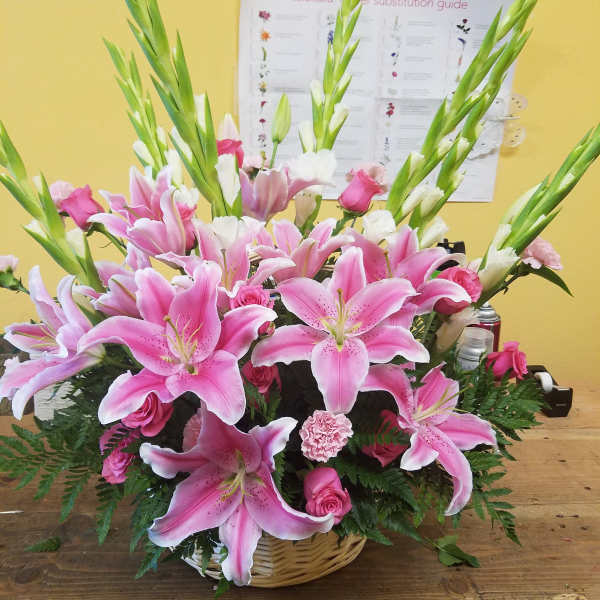 Pink lilies and roses arranged in a wicker basket