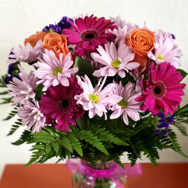 Bouquet of pink daisies and orange roses in a glass vase