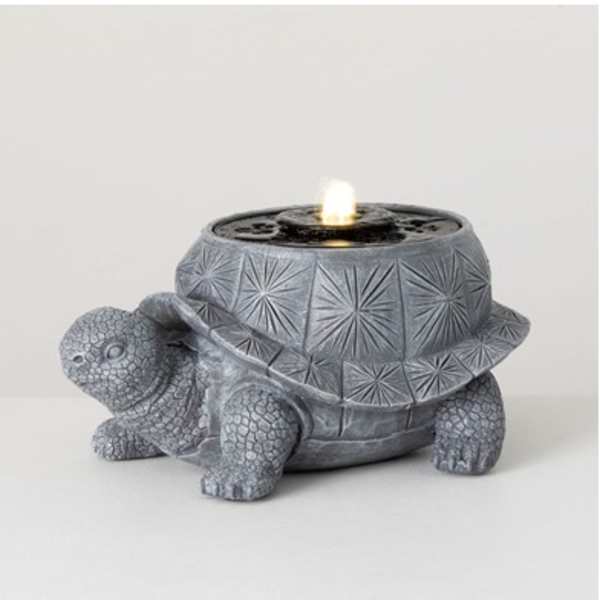 Gray turtle-shaped candle holder with a lit candle on top