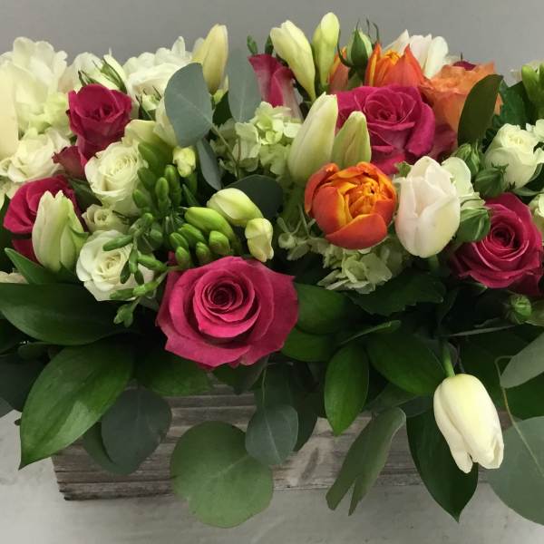 Mixed bouquet of pink roses, white tulips, and pale hydrangeas in a rectangular container