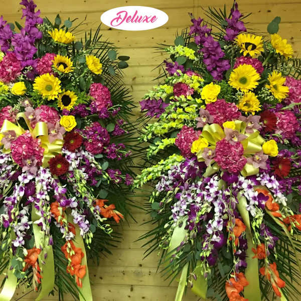 Two large standing floral sprays with yellow, pink, purple, and orange flowers