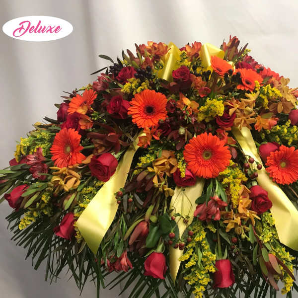Large floral spray with red roses and orange gerbera daisies, accented by yellow ribbons