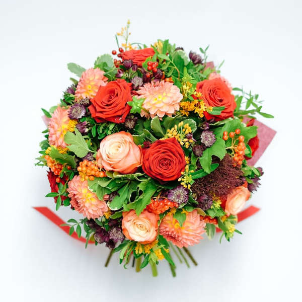 Round bouquet of red and peach roses with orange and pink blooms and berries