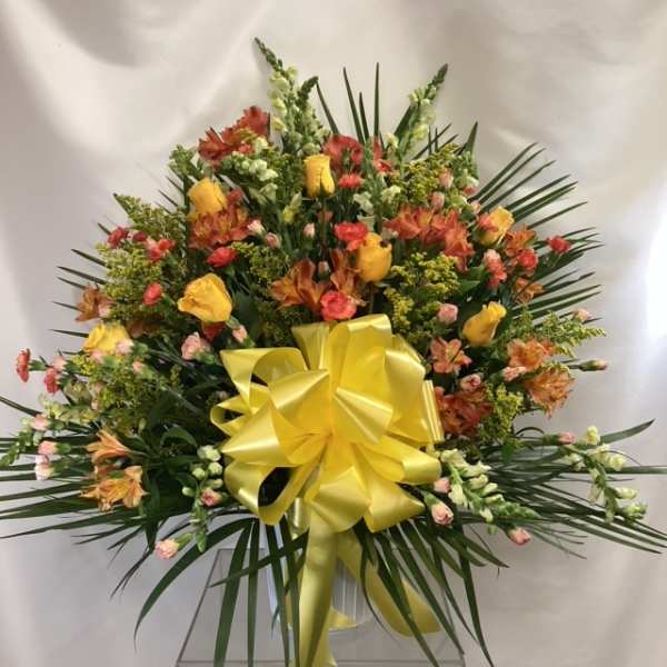 Large mixed flower arrangement with a yellow bow in a clear vase