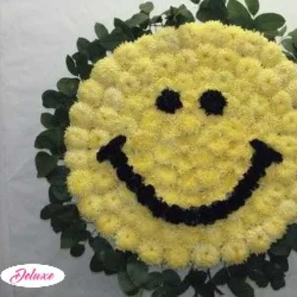 Yellow smiley-face floral wreath with dark eyes and mouth