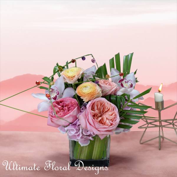 Pink and peach roses with white orchids in a glass vase
