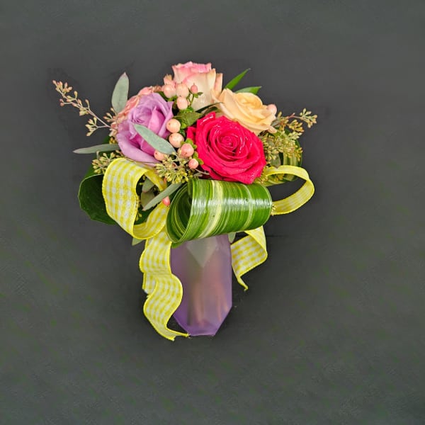 Small arrangement of multicolored roses with berries and yellow ribbon in a purple vase