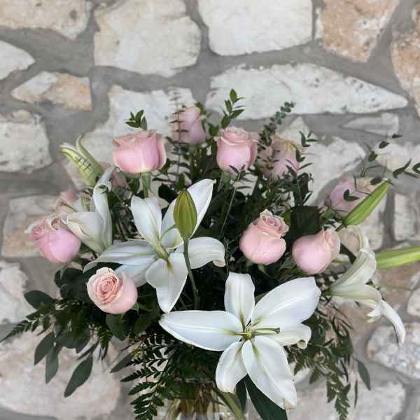 Pink roses and white lilies arranged in a clear glass vase
