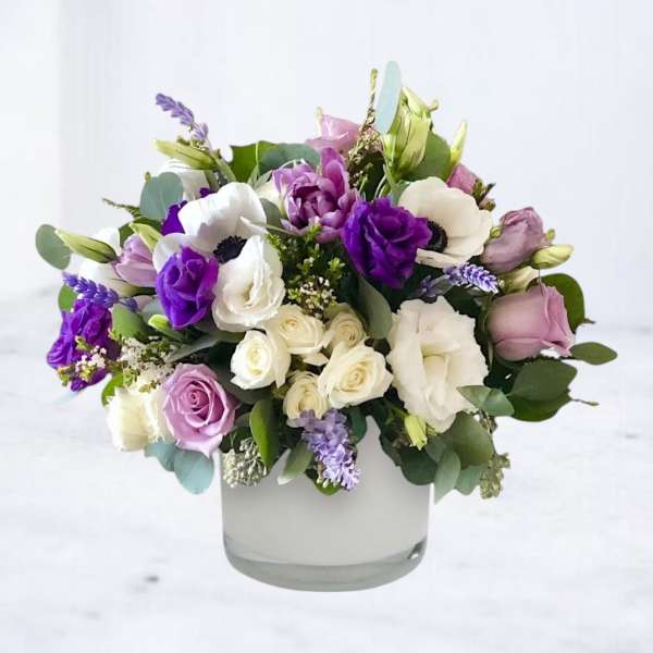 Bouquet of purple, white, and lavender flowers in a clear glass vase