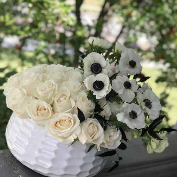 White roses and white anemones arranged in a white vase
