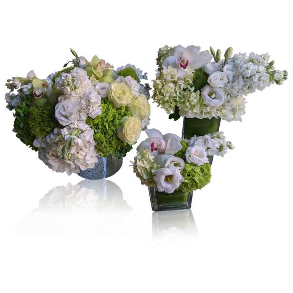 Three white floral arrangements in glass and ceramic vases