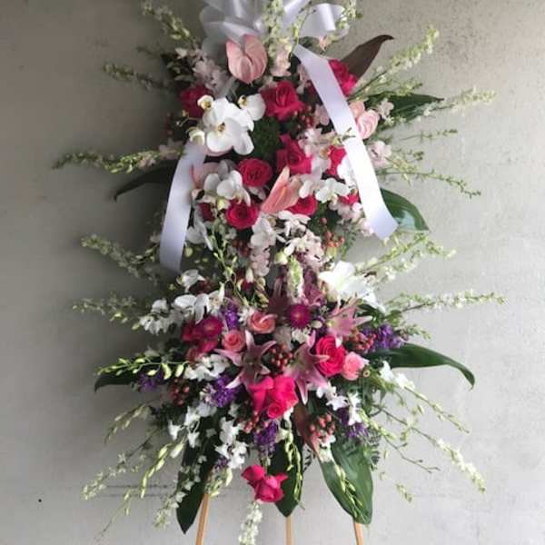 Tall standing floral spray with pink, white, and purple flowers on an easel