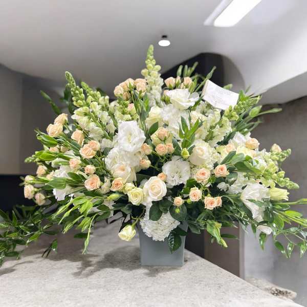 Large white and blush floral arrangement in a gray vase