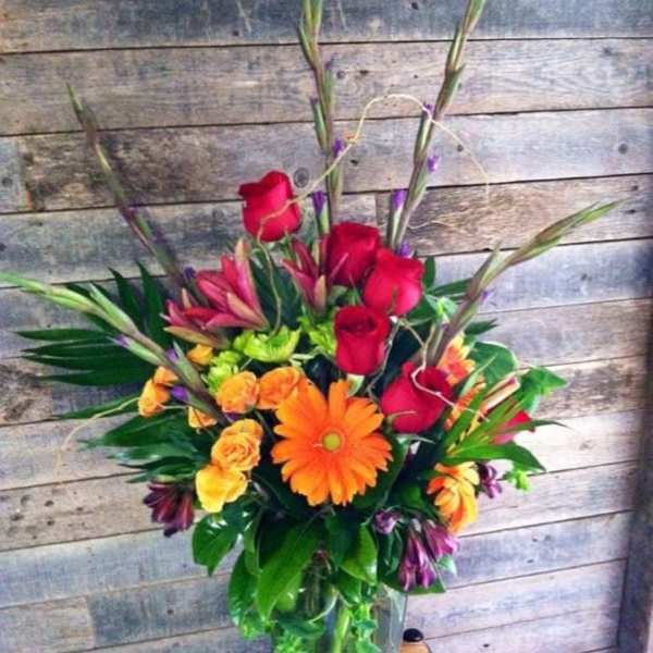 Mixed bouquet with red roses and orange gerbera daisies in a glass vase