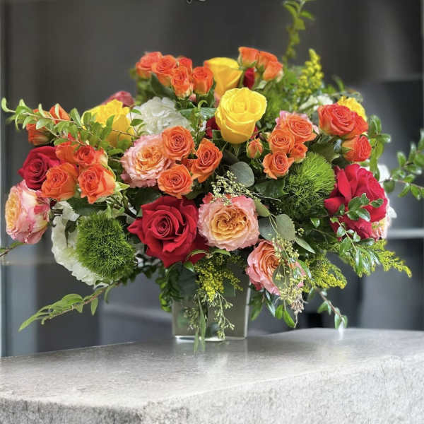 Mixed roses in a clear glass vase with greenery