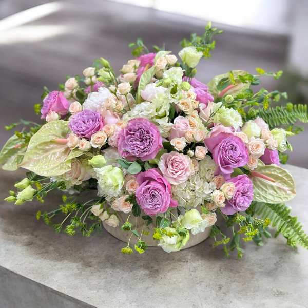 Lavender and blush floral arrangement in a low round container
