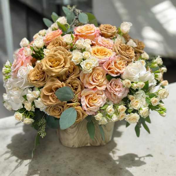 Bouquet of peach, tan, and white roses in a wrapped container