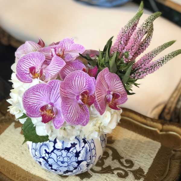 Pink orchids and white hydrangeas in a blue-and-white ceramic bowl