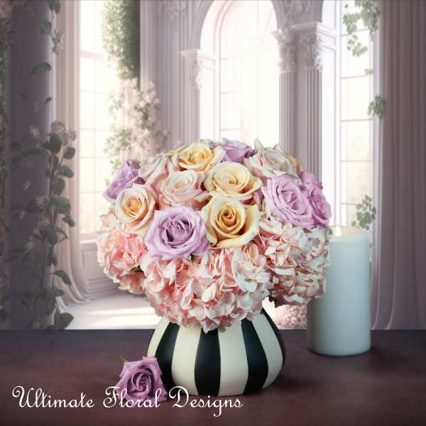 Pastel roses and hydrangeas in a striped vase with a candle nearby
