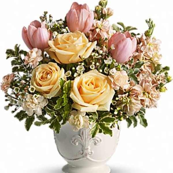Pink tulips and pale yellow roses in a white vase