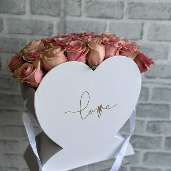 Pink roses in a white heart-shaped box with a ribbon
