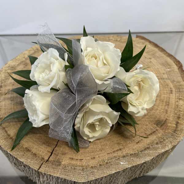 White rose bouquet with silver ribbon on a wood slice