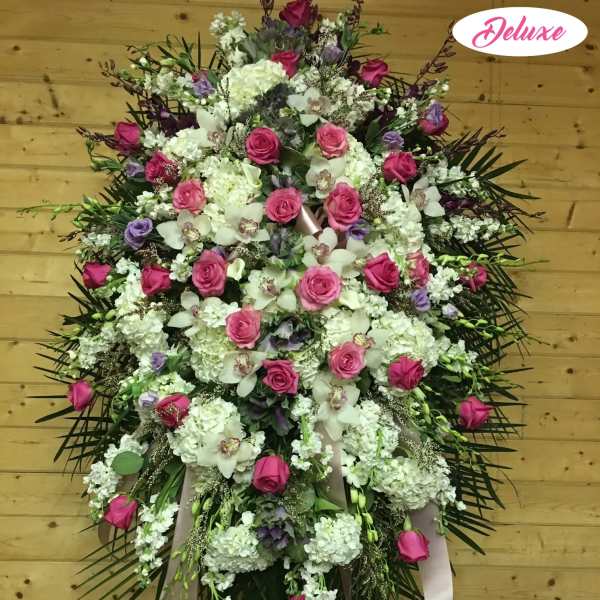 Large standing floral spray with pink roses and white blooms on a ribbon stand