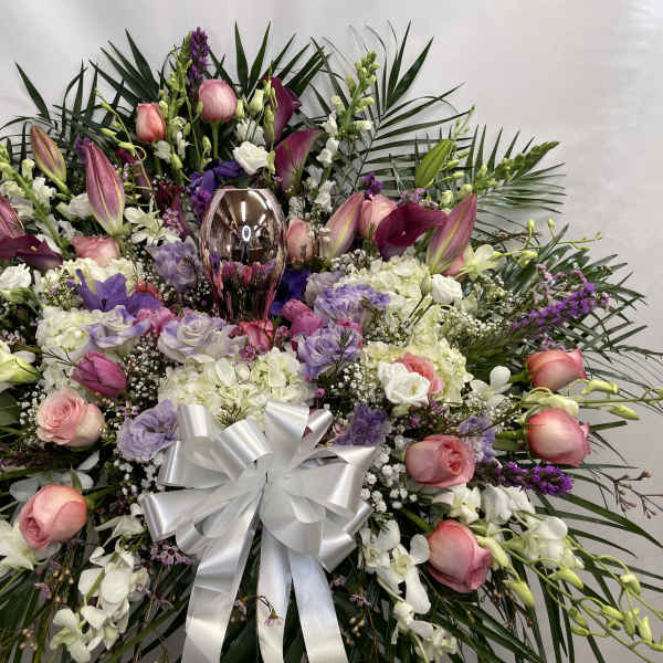 Large floral spray with pink roses, white orchids, and a silver bow